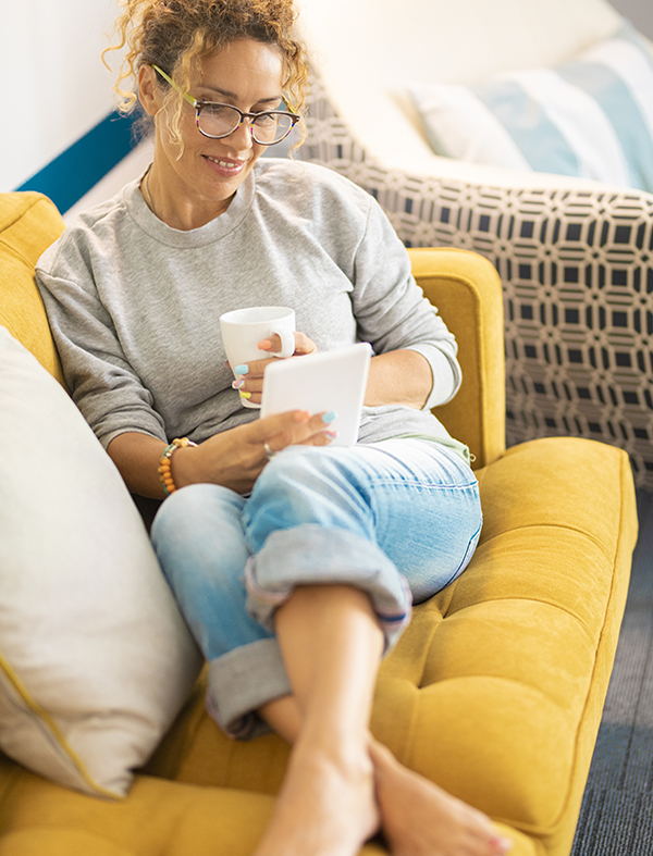 Confident Caucasian Adult Woman Sitting On The Sofa Reading A Bo